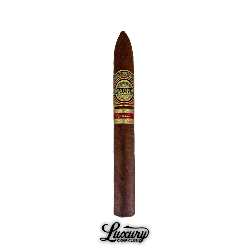 Single Quesada Vega Magna Limited Production Belicoso cigar standing upright with its gold-accented band, photographed against a white background by Luxury Cigar Club.