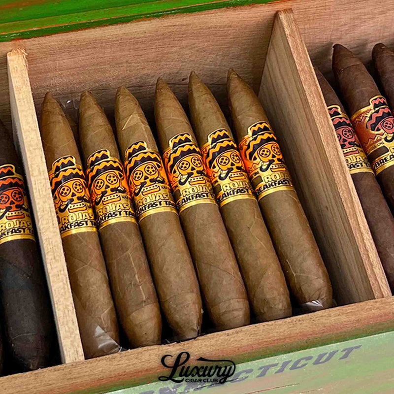 Close-up of Rojas Breakfast Tacos Connecticut Petite Salomon cigars highlighting the golden-brown wrapper and detailed band design with the signature skull logo, featured by Luxury Cigar Club.