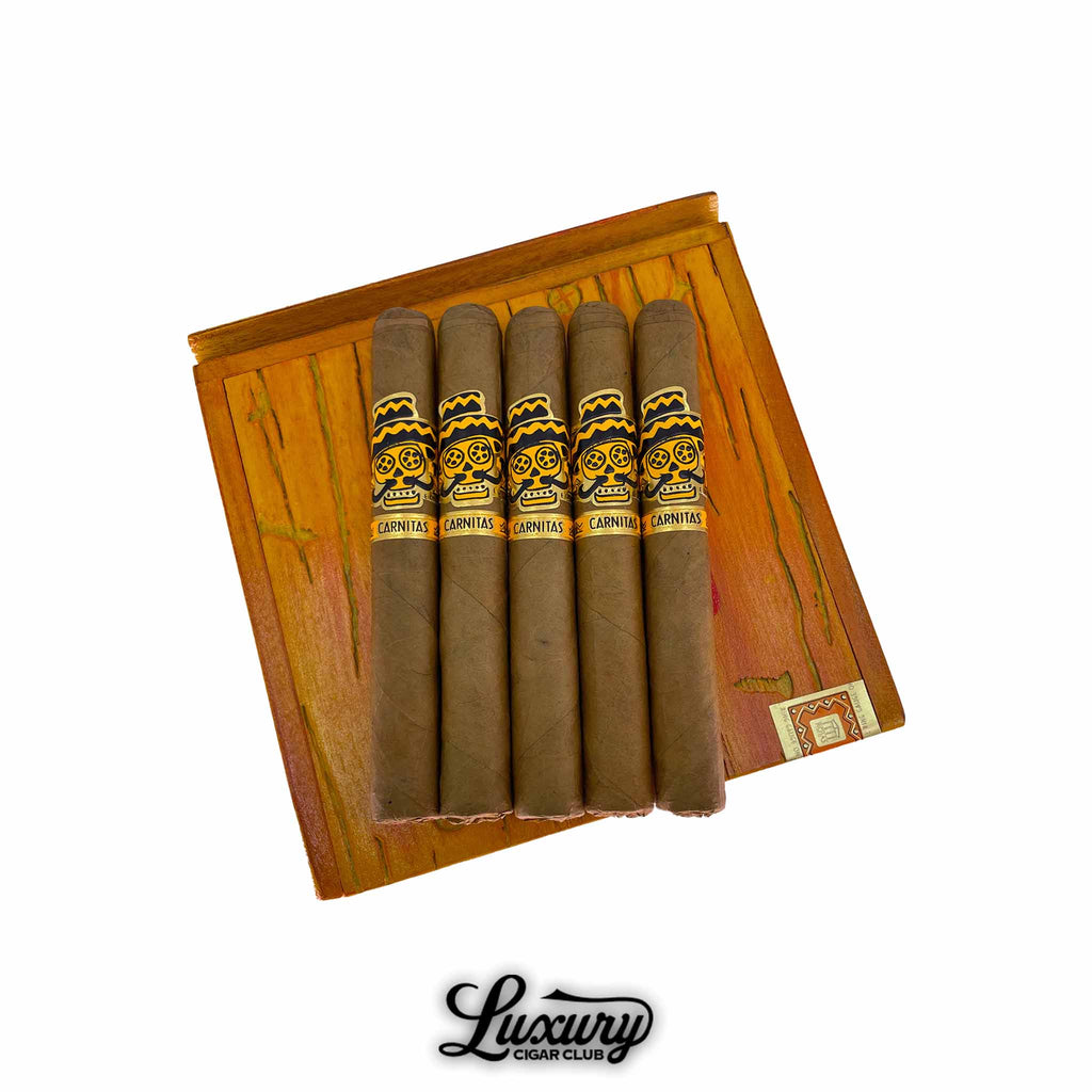 Rojas Street Tacos Carnitas Short Corona cigars resting on a wooden box lid with colorful grain detail, showcasing vibrant yellow and black bands with skull artwork, presented by Luxury Cigar Club.