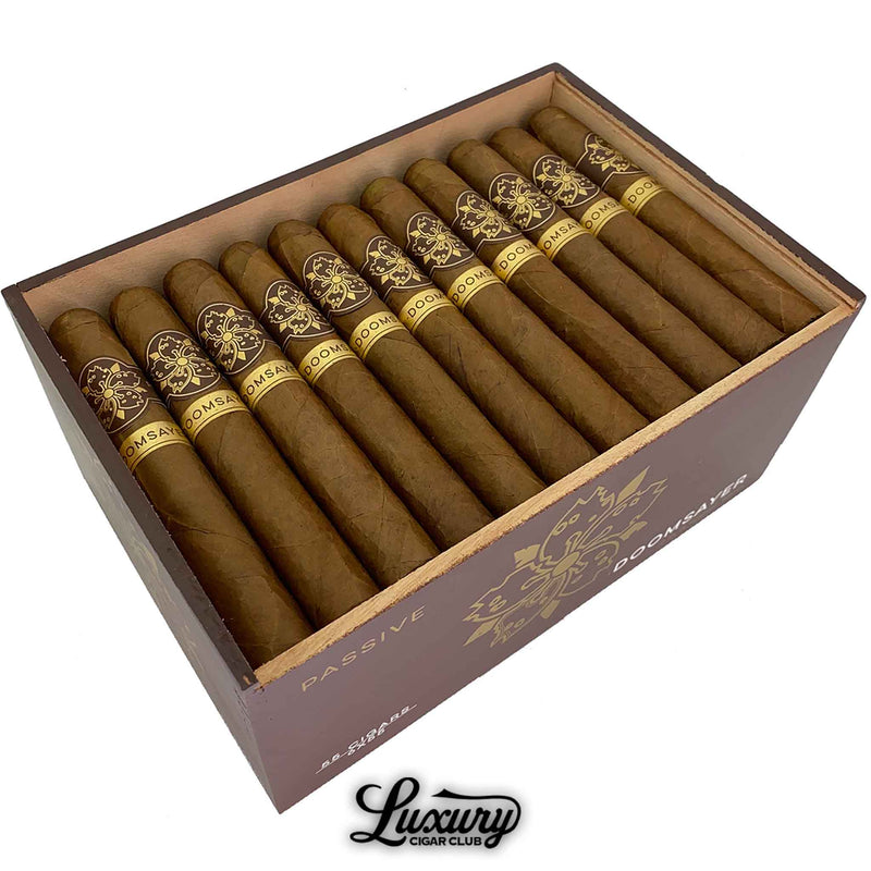 Close-up of Room101 Doomsayer Passive Claro cigars inside a wooden box, showing detailed gold and brown cigar bands.