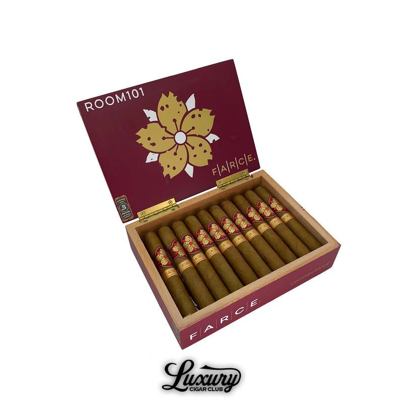 Open box of Room 101 Farce Connecticut Robusto cigars displayed by Luxury Cigar Club with golden floral design on the lid and neatly arranged cigars inside.