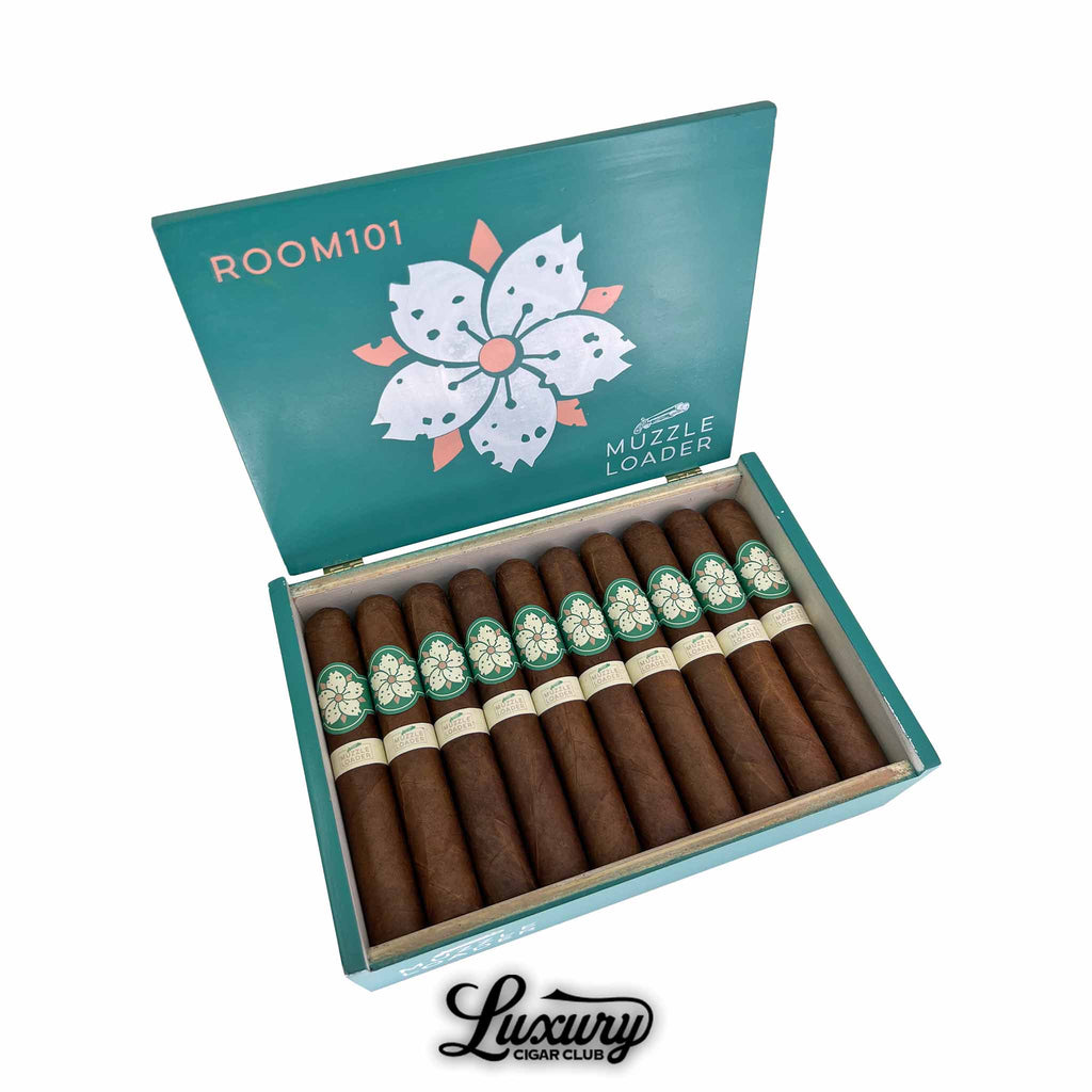 Open box of Room101 Muzzle Loader Gordo cigars from Luxury Cigar Club, showing neatly arranged dark brown cigars with green and cream floral bands inside a teal and white branded box lid.