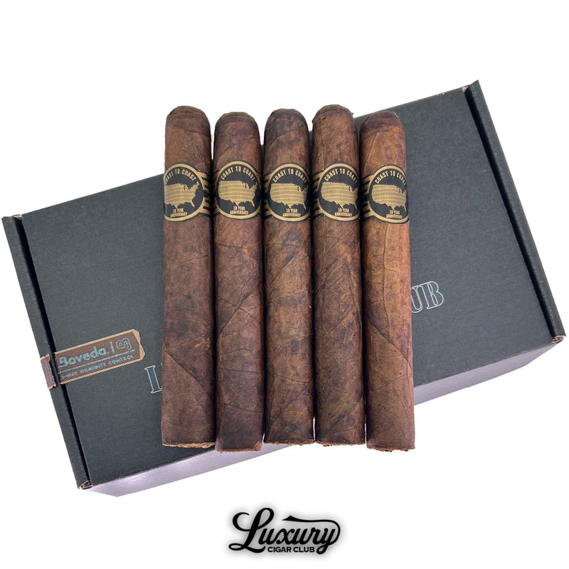 Close-up of five Sinistro 10 Year Anniversary toro cigars with rich dark wrapper leaf, gold USA silhouette bands, and oily Maduro texture, arranged on a Luxury Cigar Club mailer box.