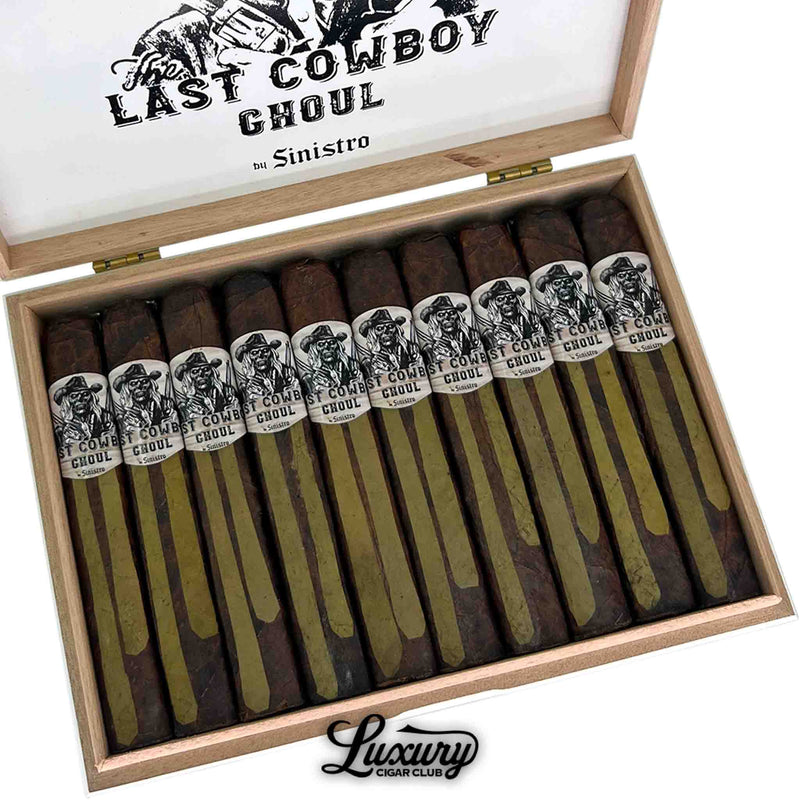 Close-up of an open wooden box of Sinistro The Last Cowboy Ghoul Toro cigars showing dark barber pole wrappers with green and brown tones and bold illustrated bands featuring a skeletal cowboy. Luxury Cigar Club logo below.