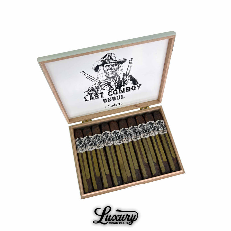 Open box of Sinistro The Last Cowboy Ghoul Toro cigars featuring barber pole wrappers in green and brown hues with illustrated cowboy bands and white box lid branding. Luxury Cigar Club logo below.