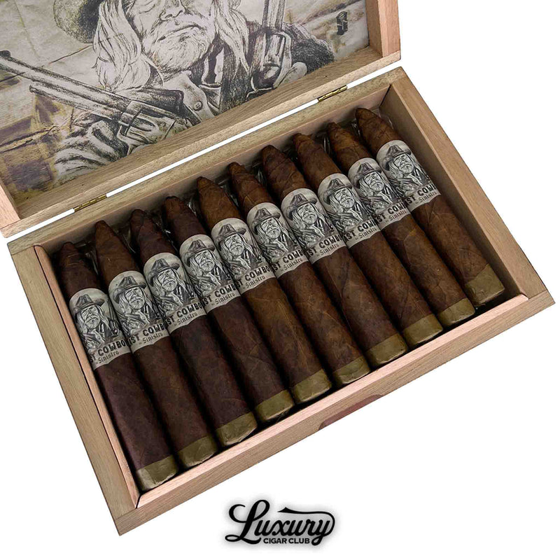 Close-up of an open wooden box displaying twelve Sinistro The Last Cowboy Maduro Petite Belicoso cigars. Each cigar features a tapered head and a closed foot, with detailed black-and-white cowboy-themed bands. The cigars are neatly arranged above the Luxury Cigar Club logo, with a sepia-toned cowboy illustration partially visible on the inside lid.