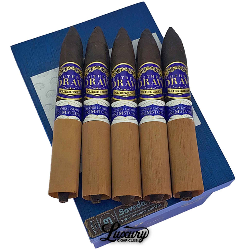 Close-up image of Southern Draw Jacob’s Ladder Brimstone cigars in cedar sleeves on top of a blue box, shot for Luxury Cigar Club online cigar retail.