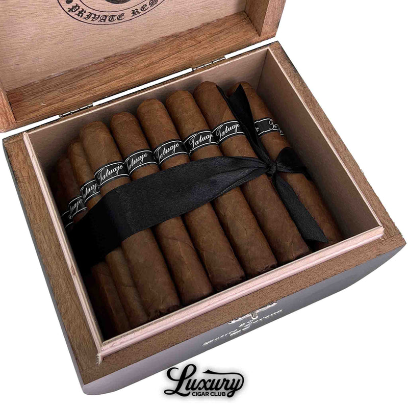 Close up of Tatuaje Black Petite Corona Black Crack cigars with black bands and ribbon inside box from Luxury Cigar Club