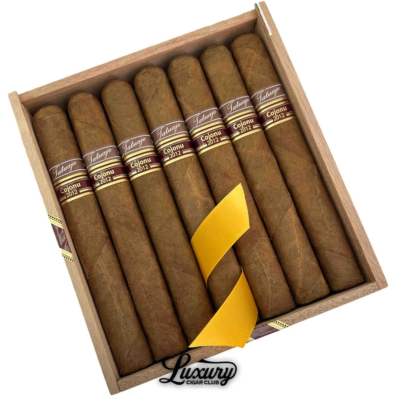 Close up view of Tatuaje Cojonu 2012 Corojo cigars in the box with yellow ribbon at Luxury Cigar Club