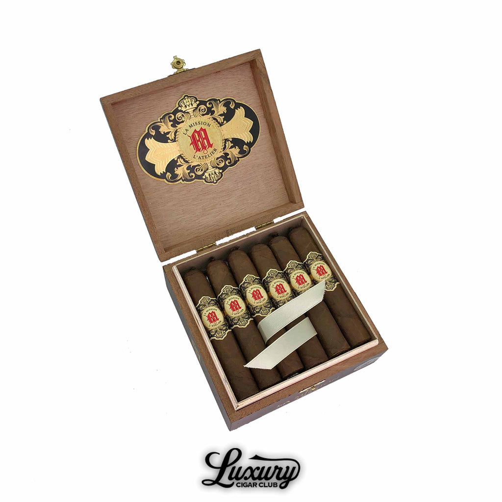 Open box of Tatuaje La Mission de L’Atelier 1959 cigars with ornate gold and red banding presented by Luxury Cigar Club