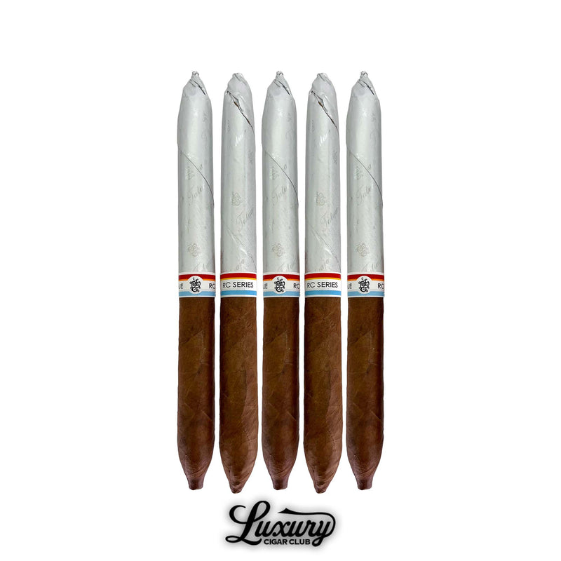 Five pack of Tatuaje RC 233 Gran Perfecto cigars from Luxury Cigar Club featuring long tapered cigars partially wrapped in silver foil with red white and blue band accents.