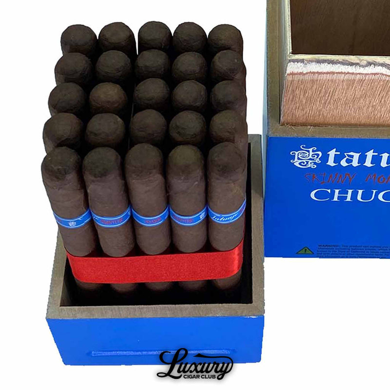 Close-up view of Tatuaje Skinny Monsters Chuck petit lancero cigars stacked tightly in rows, showcasing their dark wrappers, blue cigar bands, and the blue wooden display box with bold Tatuaje Skinny Monsters Chuck lettering, captured for Luxury Cigar Club.