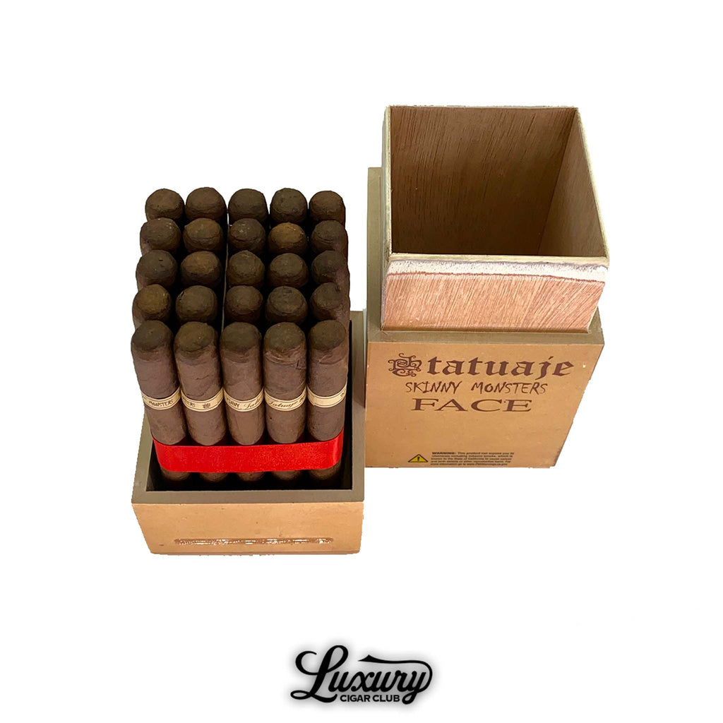 Open box of Tatuaje Skinny Monsters Chuck cigars from Luxury Cigar Club, showing a square wooden monster-themed container with blue exterior branding and a full bundle of petit lancero cigars secured with a red ribbon.