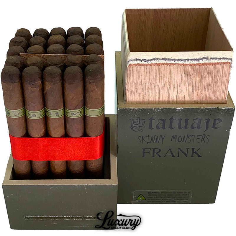 Close up of Tatuaje Skinny Monsters Frank cigars bundled tightly with a red ribbon inside the open olive green box, showing the green bands and rustic wrapper for Luxury Cigar Club.