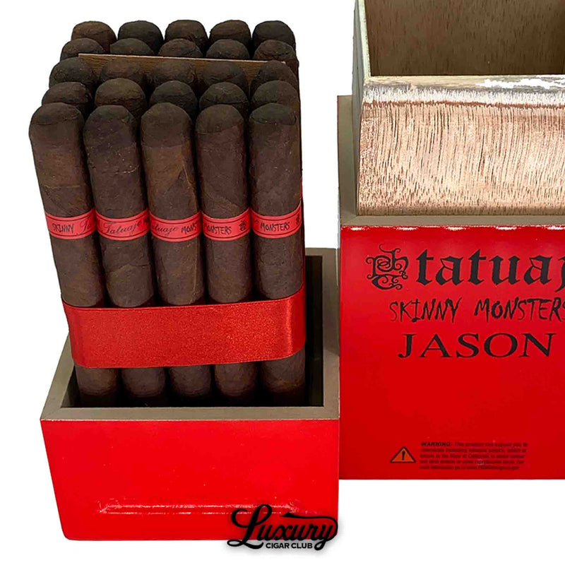 Close-up of Tatuaje Skinny Monsters Jason petit lancero cigars inside a red wooden box, displaying dark oily wrappers, red cigar bands marked “Monsters,” and a bold red ribbon securing the bundle, with the box lid removed to show wood grain interior and the Luxury Cigar Club logo beneath.