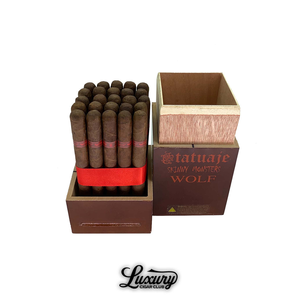 Open box of Tatuaje Skinny Monsters Wolf petit lancero cigars displayed in a brown wooden monster series crate with red ribbon bundle inside, photographed for Luxury Cigar Club.