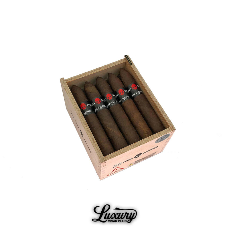 Open cedar box of Tatuaje Surrogates Skull Breaker Belicoso cigars, each wrapped in dark brown tobacco with black bands featuring a red skull, displayed for sale at Luxury Cigar Club.