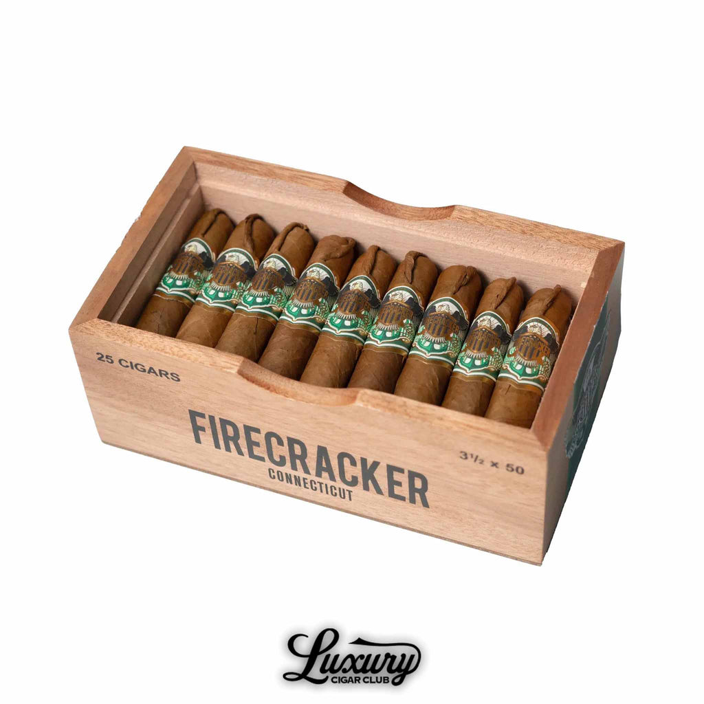 Open wooden box of United Firecracker Connecticut cigars arranged neatly in rows, featuring a light brown wrapper and ornate green and gold cigar bands. The box is labeled “Firecracker Connecticut” with “25 cigars” and “3 1/2 x 50” markings. Luxury Cigar Club logo displayed below.