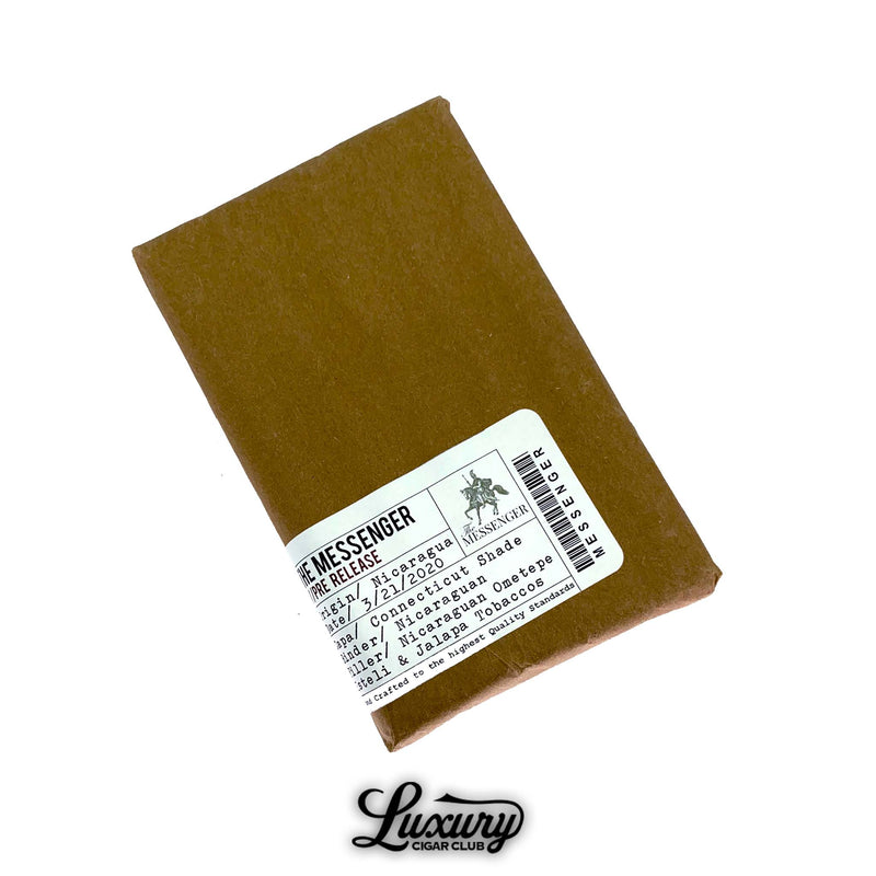 Close-up of Valacari The Messenger cigar pack with label showing blend details including Connecticut Shade wrapper, Nicaraguan binder and filler, and production information. Luxury Cigar Club logo beneath.