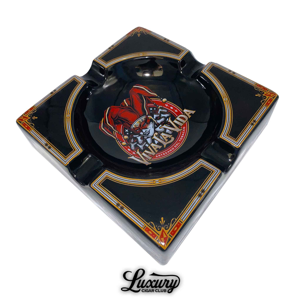 Viva La Vida ceramic ashtray featuring a bold jester logo in the center with ornate red and gold detailing on a glossy black finish.