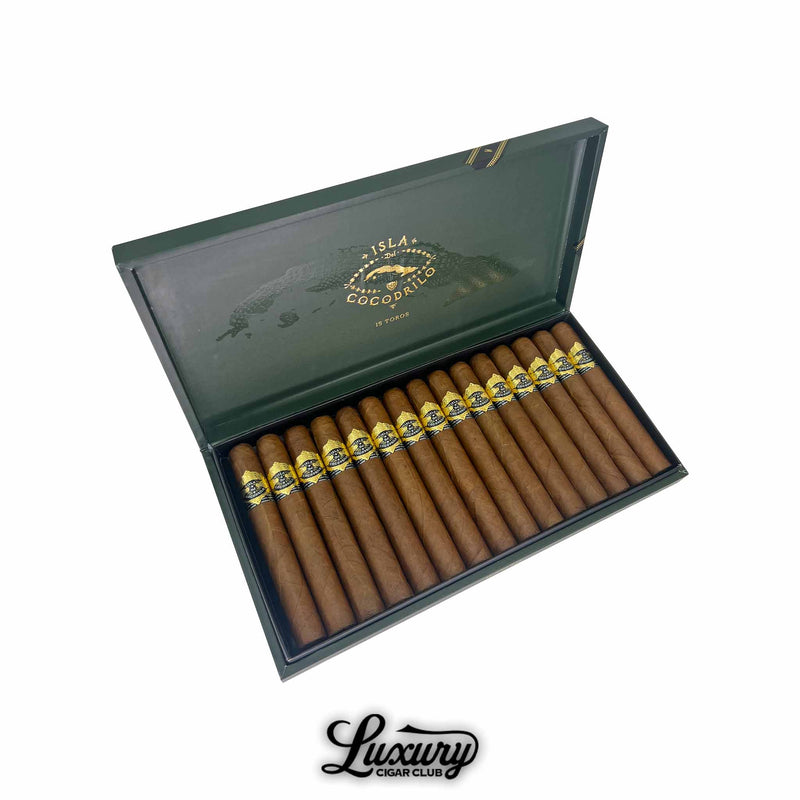 Open box of Warped Isla Del Cocodrilo Toro cigars, showing 15 cigars with golden bands inside a dark green box marked with gold branding and a crocodile illustration.