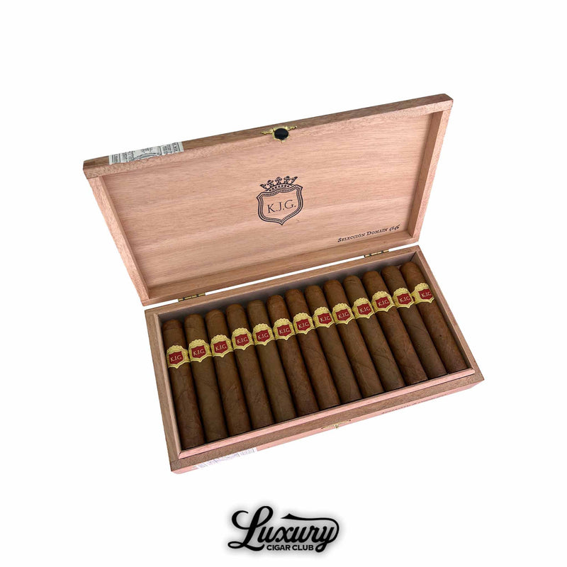 Open wooden box of Warped Selección Domain 4546 cigars angled on white background, showing a full row of cigars with red and gold KJG bands and the Luxury Cigar Club logo underneath.