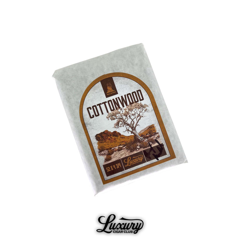 Wildfire Cottonwood cigar pack wrapped in white paper with a rustic desert landscape label featuring a cottonwood tree and Luxury Cigar Club branding.