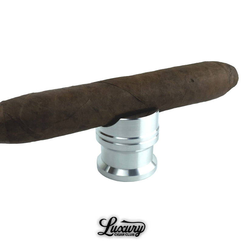 Zimmer Maverick raw silver cigar rest supporting a hand-rolled cigar, durable aluminum accessory offered by Luxury Cigar Club.